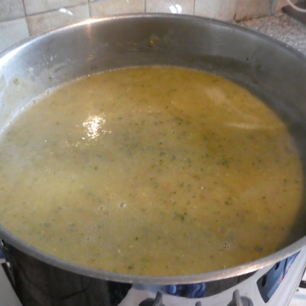A large steel pot with greeny coloured Courgette Soupcourget