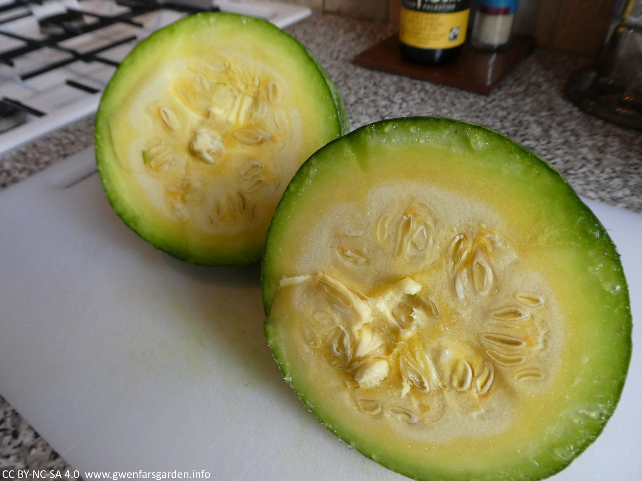 A smaller pumpkin cut in half and sitting on a bench in the kitchen. It has yellow, rather than orange, flesh, but still tastes really good.