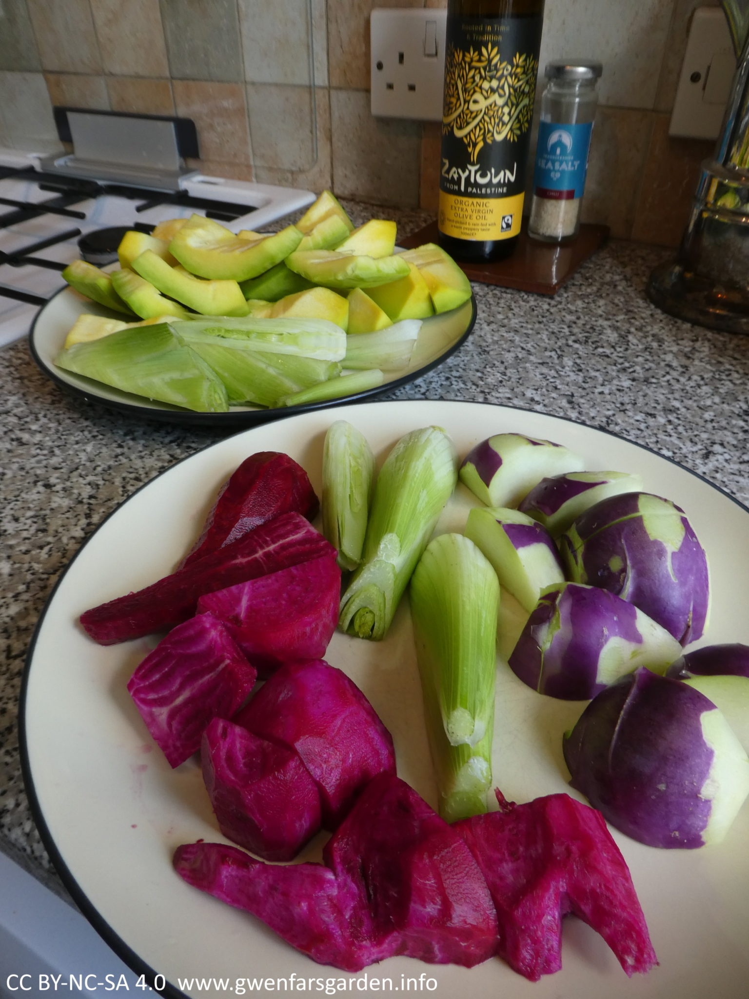 Two plates of veggies peeled and cut up, from the garden. The top one has the small yellow Sibley squash cut up, plus some fennel bulbs. The bottom one has purple kohlrabi and red-magenta beetroot.