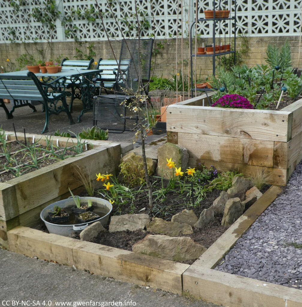 An overview of the scree bed all filled in and several large flat stones standing up and plants will be grown inbetween these.