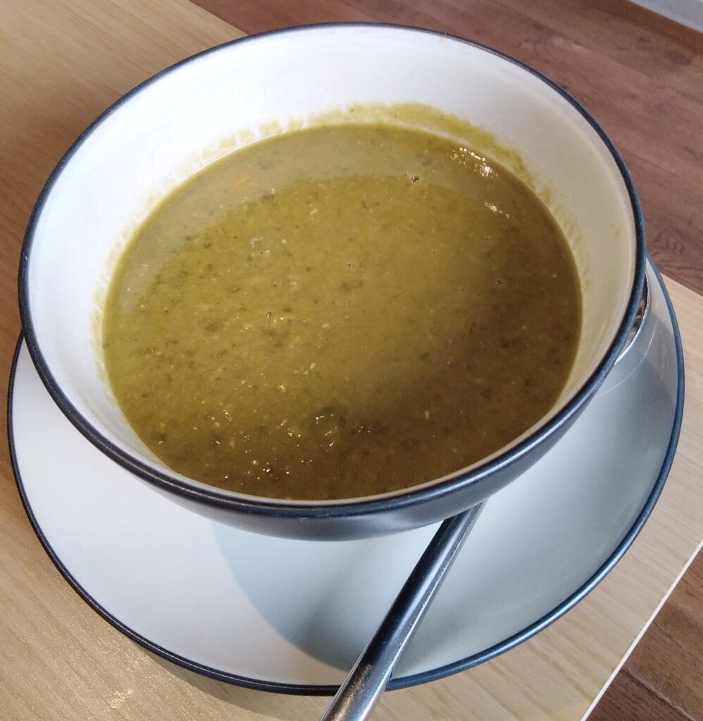 A soup bowl with a green creamy sorrel and lentil soup in it.